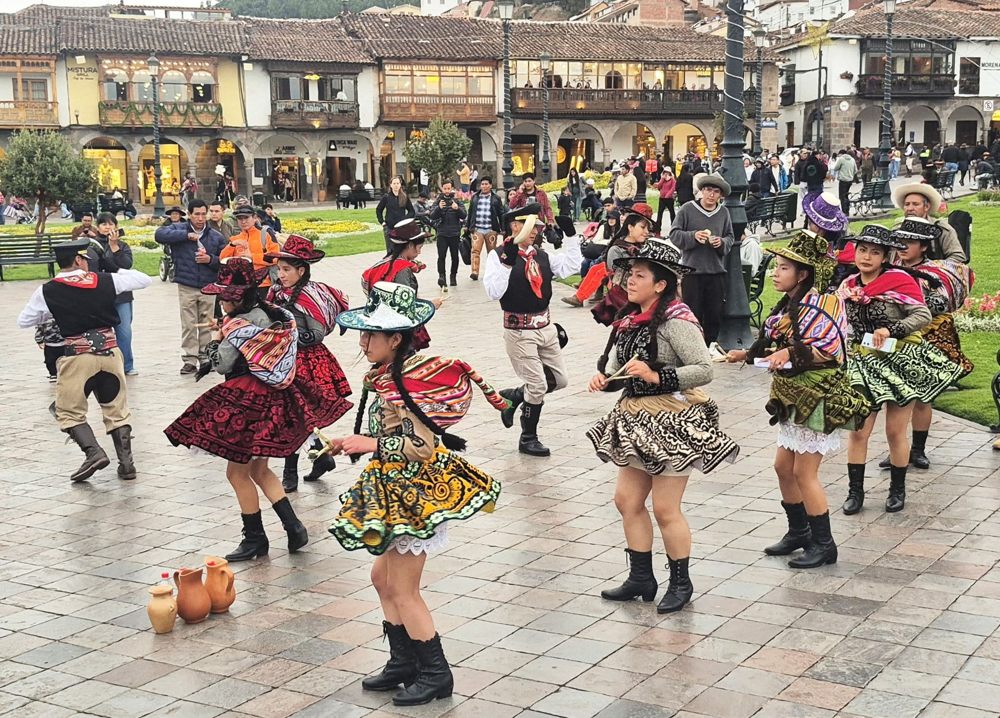 Group of dancers in colorful traditional dress performing in Plaza de Armas, Cusco, Peru during a street festival.