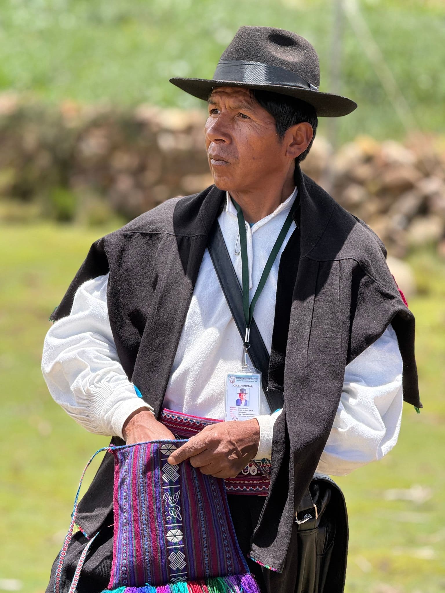 Lake Titicaca island scene with a man in traditional Andean clothing adjusting a woven bag