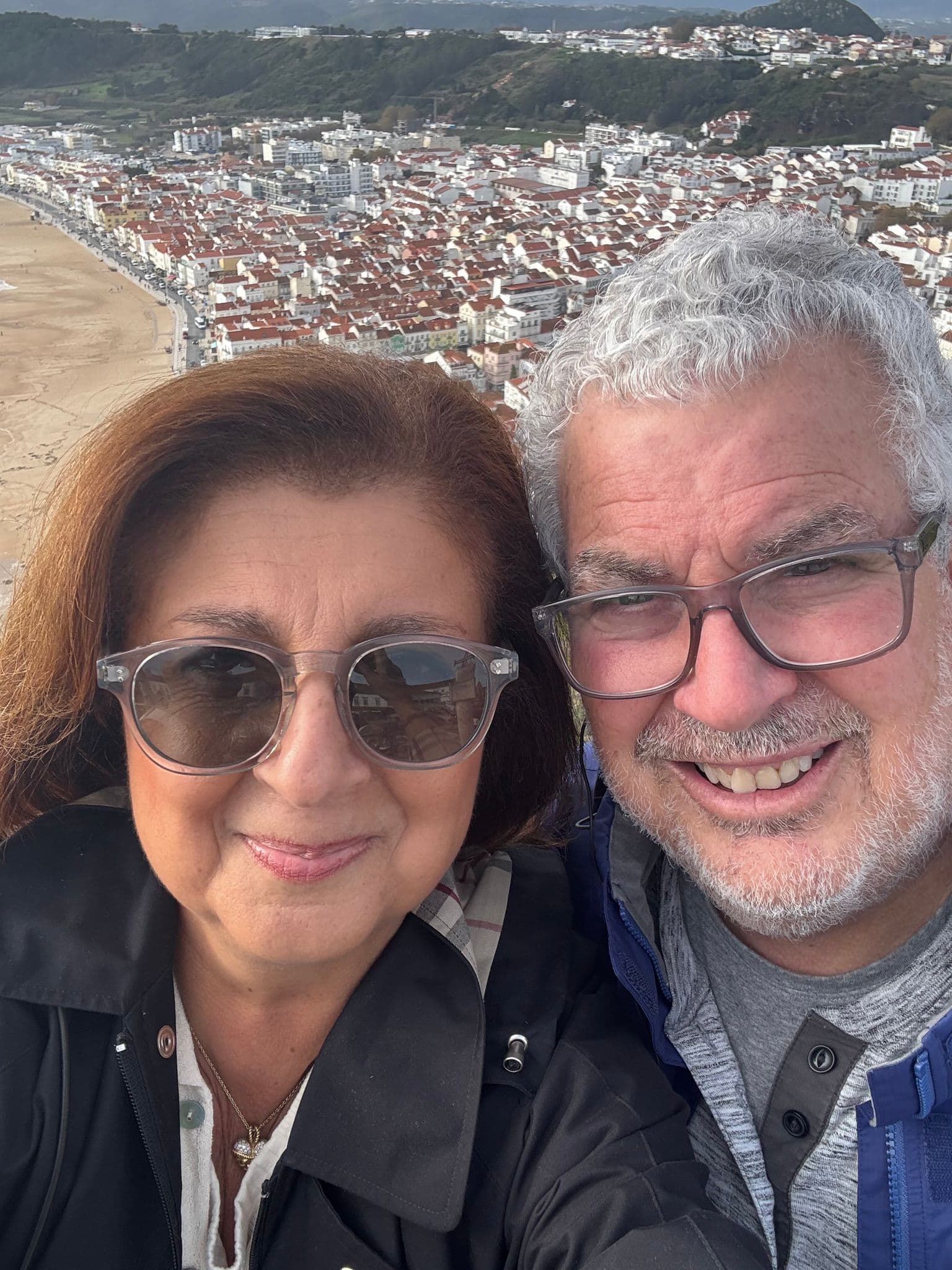 Sítio da Nazaré viewpoint overlooking Nazaré town and beach, with two travelers taking a selfie, Nazaré, Portugal.