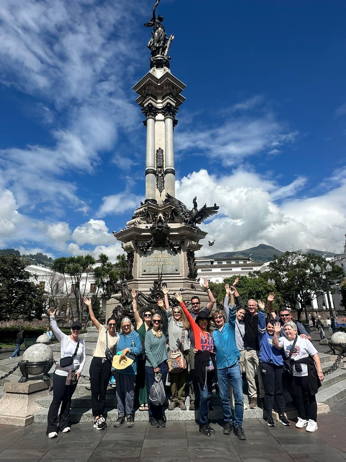 Independence Monument in Plaza de la Independencia, Quito, Ecuador with a tour group standing and waving in front of the column